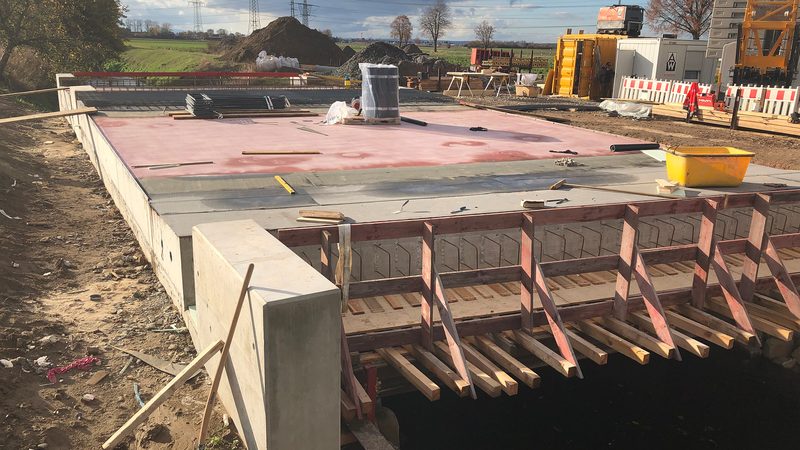 Neu betoniertes Brückenbauwerk mit Schalung und Widerlager an einem Feldweg